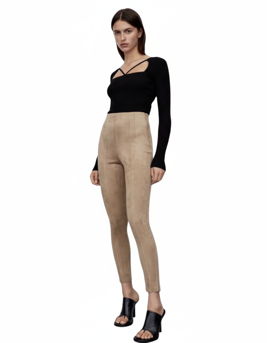 Woman wearing a black top and beige pants on a white background