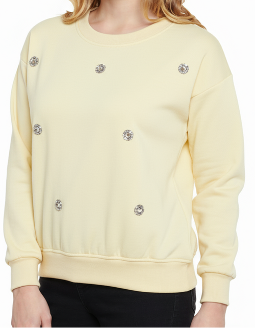 Light yellow sweatshirt with decorative buttons on a white background
