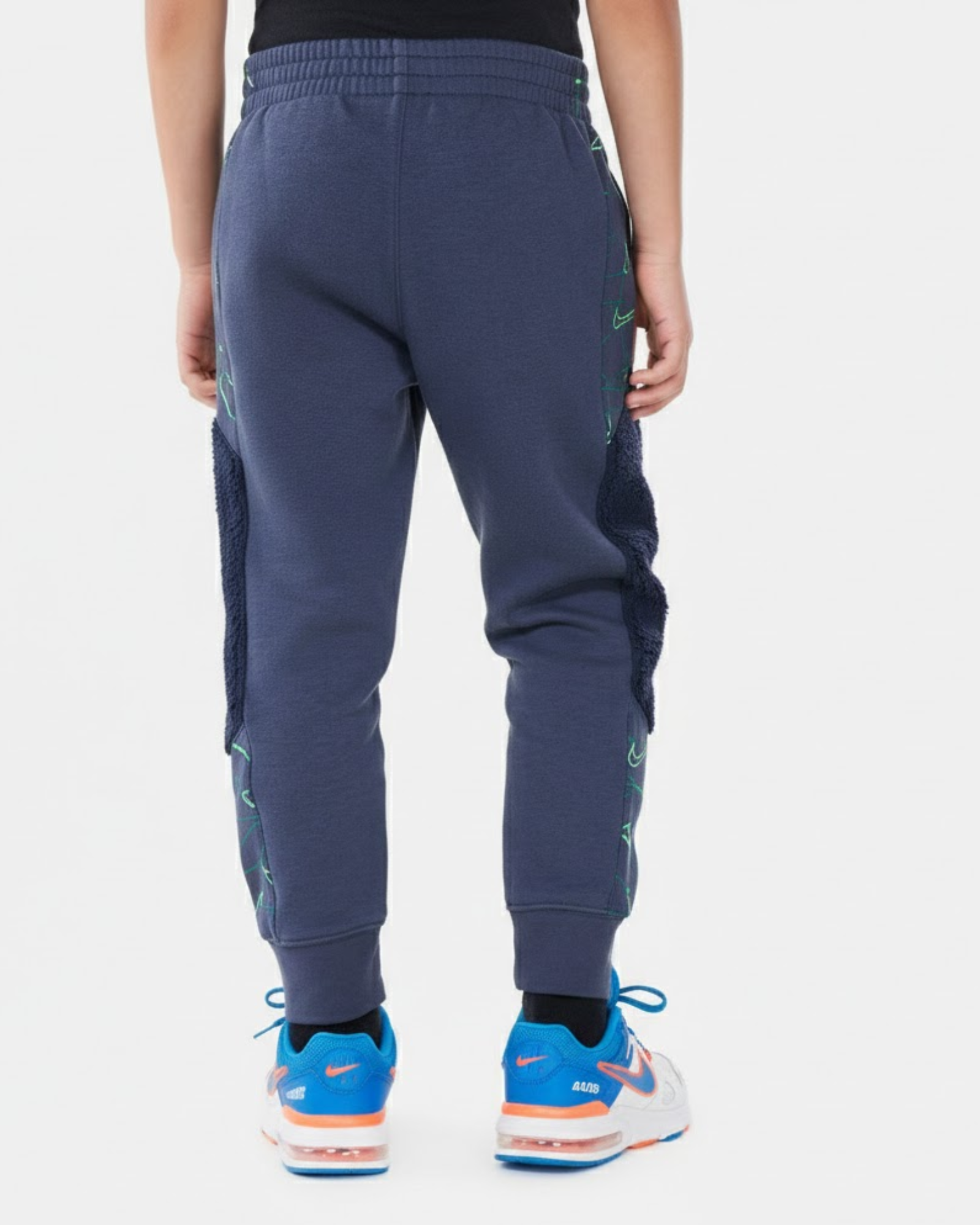 Person wearing blue jogger pants with green accents on a white background