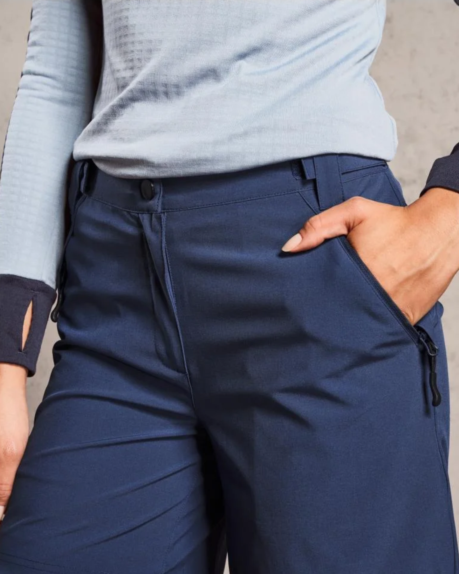 Person wearing navy pants with a light blue top against a neutral background