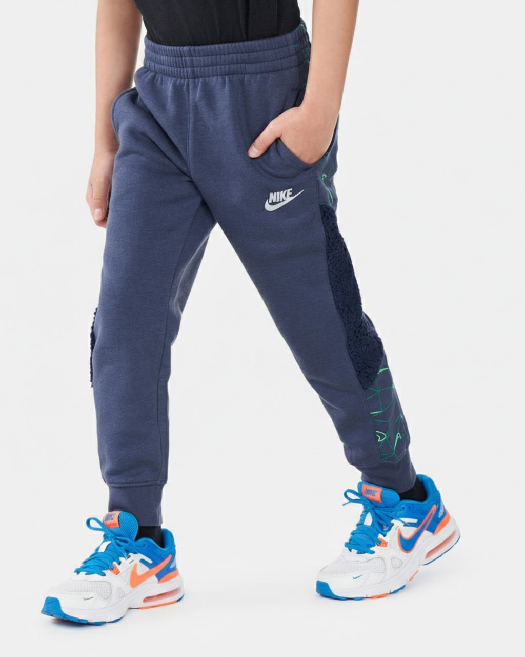 Child wearing navy Nike sweatpants and colorful sneakers on a white background