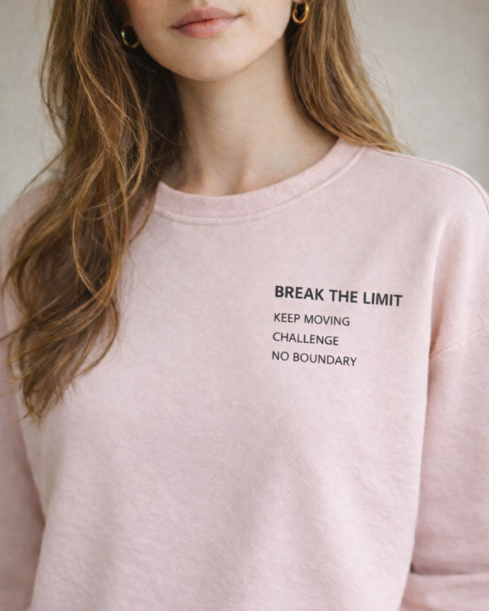 Person wearing a pink sweatshirt with motivational text on a neutral background