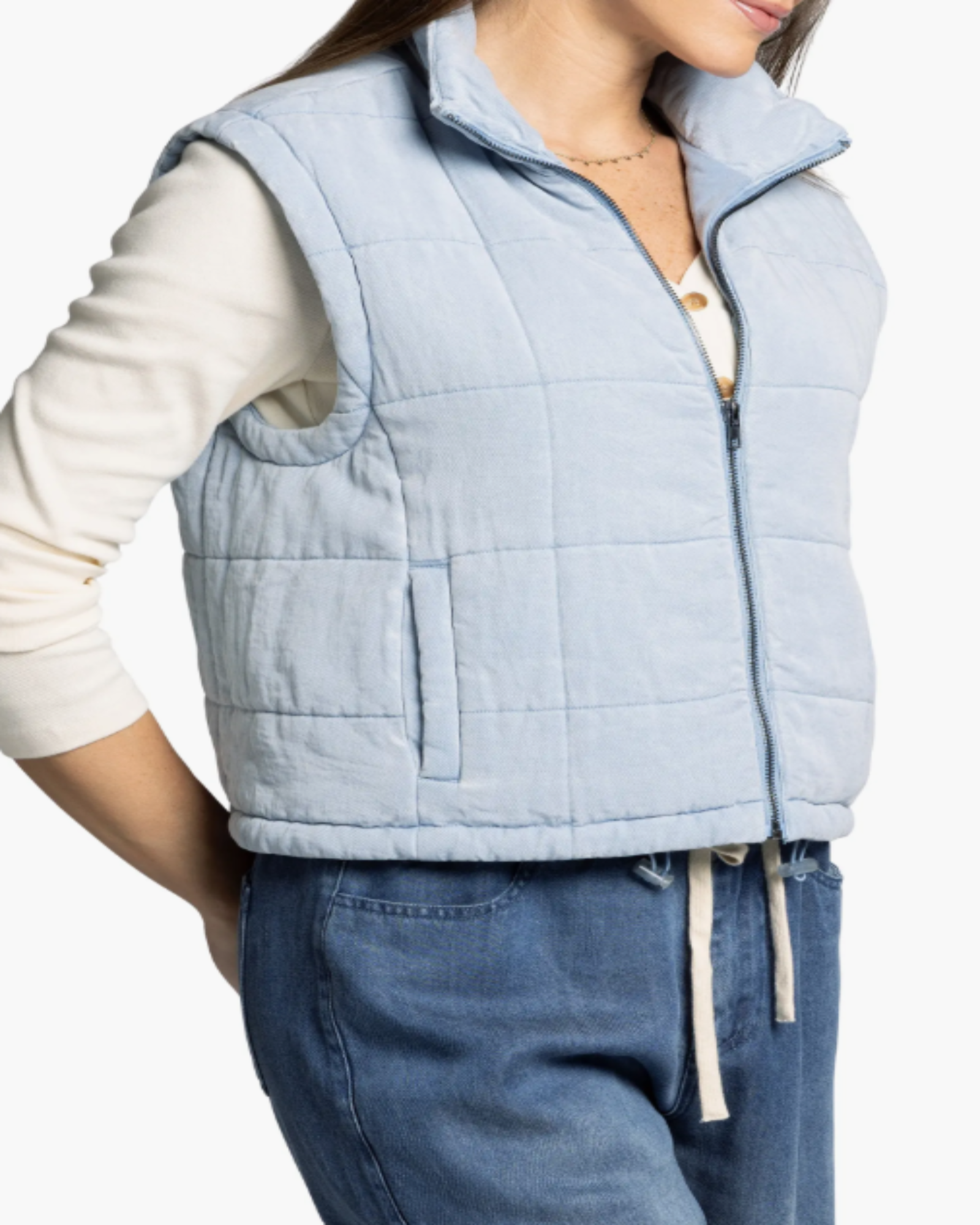 Light blue quilted vest worn by a person on a white background
