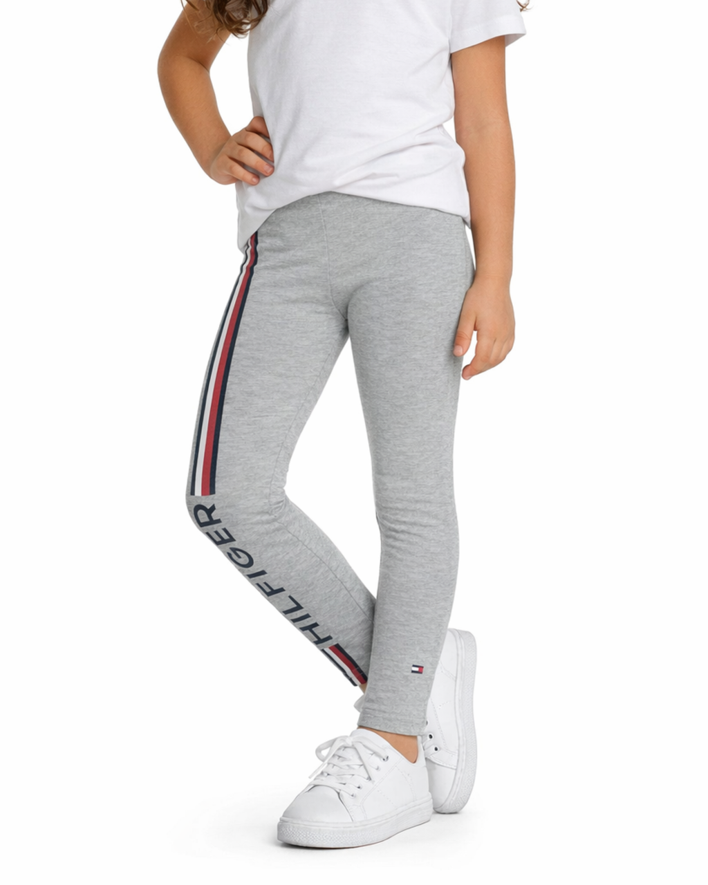 Person wearing gray sweatpants with a brand logo and white sneakers on a white background