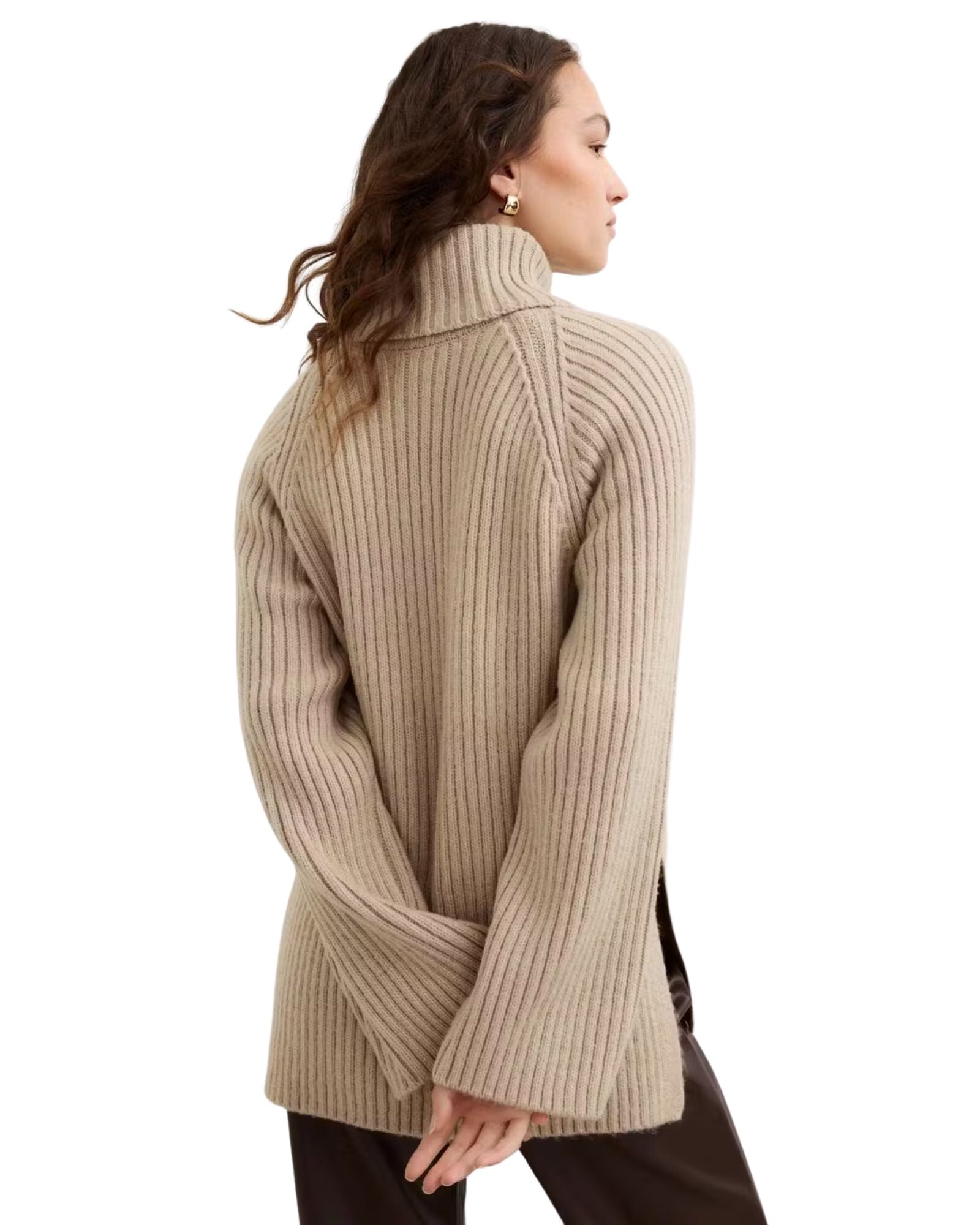 Woman wearing a beige ribbed sweater on a white background