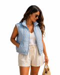 Woman wearing a light blue puffer vest over a white top and beige shorts on a white background
