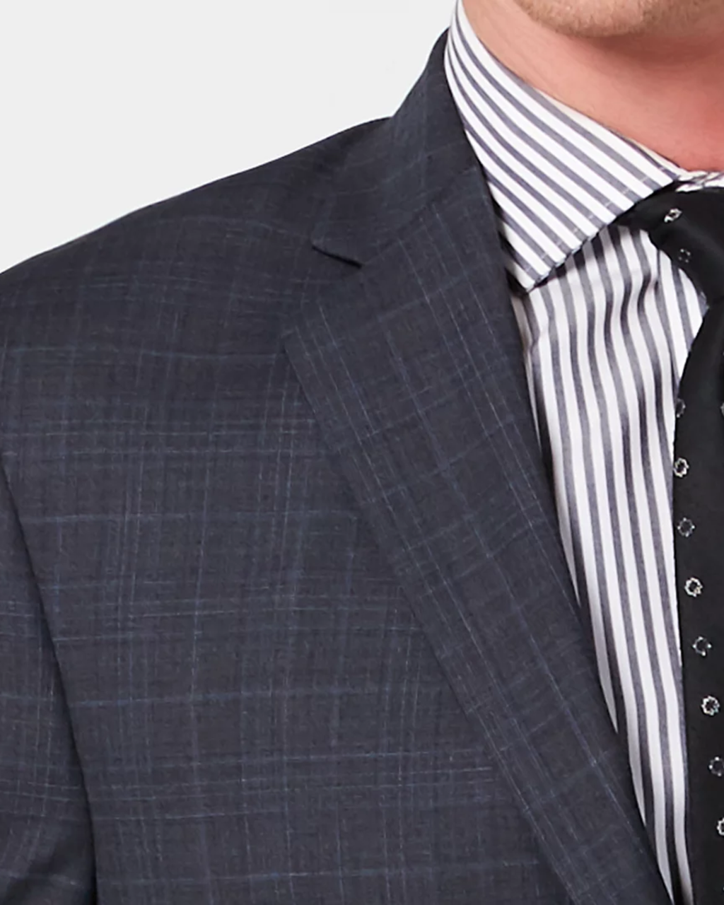 Gray checkered suit jacket over a striped shirt with a black tie on a light gray background