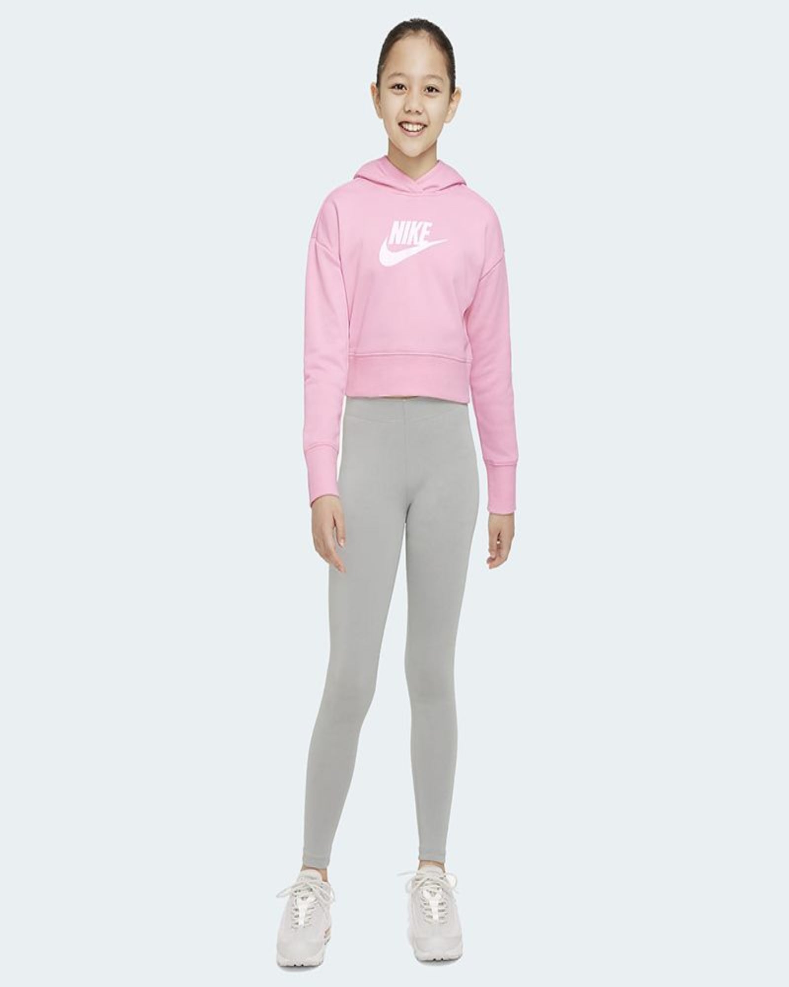 Child wearing a pink Nike hoodie and gray leggings on a white background