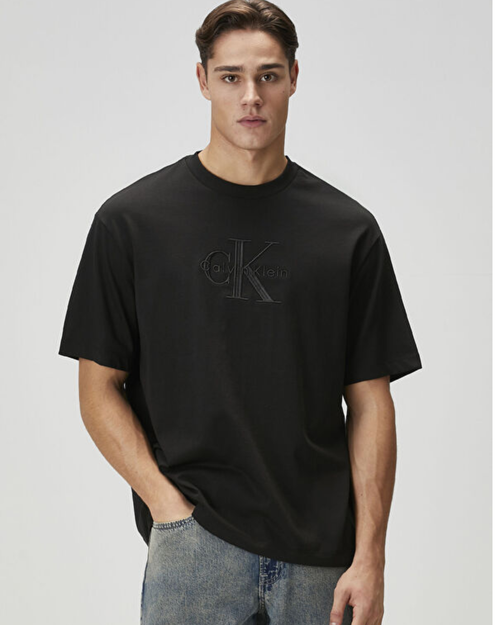 Man wearing a black Calvin Klein t-shirt on a gray background