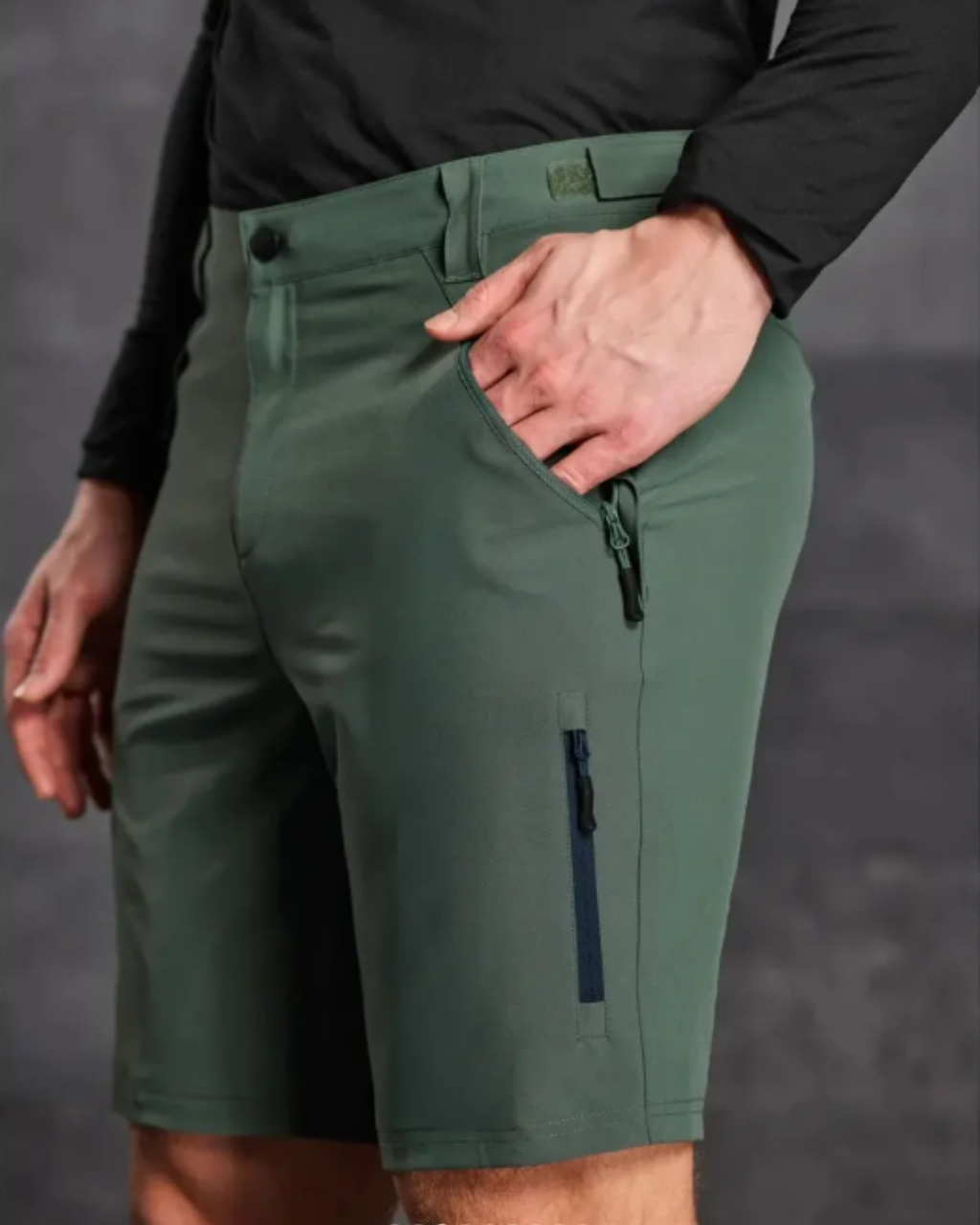 Green shorts with a black long-sleeve shirt on a gray background
