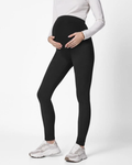 Pregnant Mother wearing black leggings and white sneakers on a white background