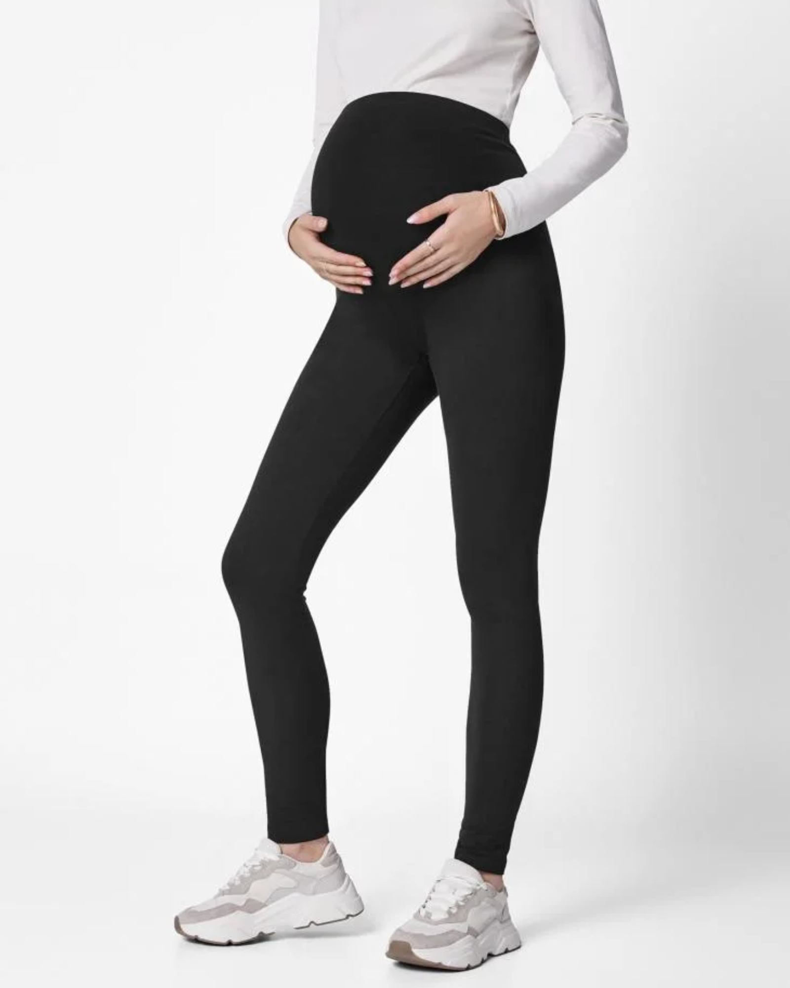 Pregnant Mother wearing black leggings and white sneakers on a white background