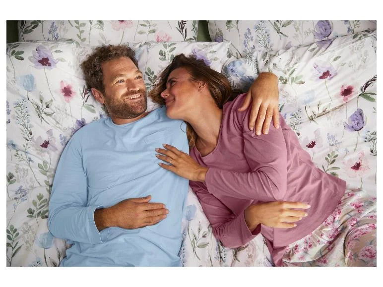 Man and woman lying on a bed with floral bedding wearing pajama 