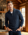 Man wearing a blue sweater in a cozy indoor setting with wooden walls and a stone fireplace.