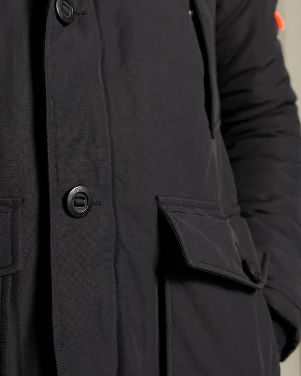 Close-up of a dark coat with buttons and a pocket