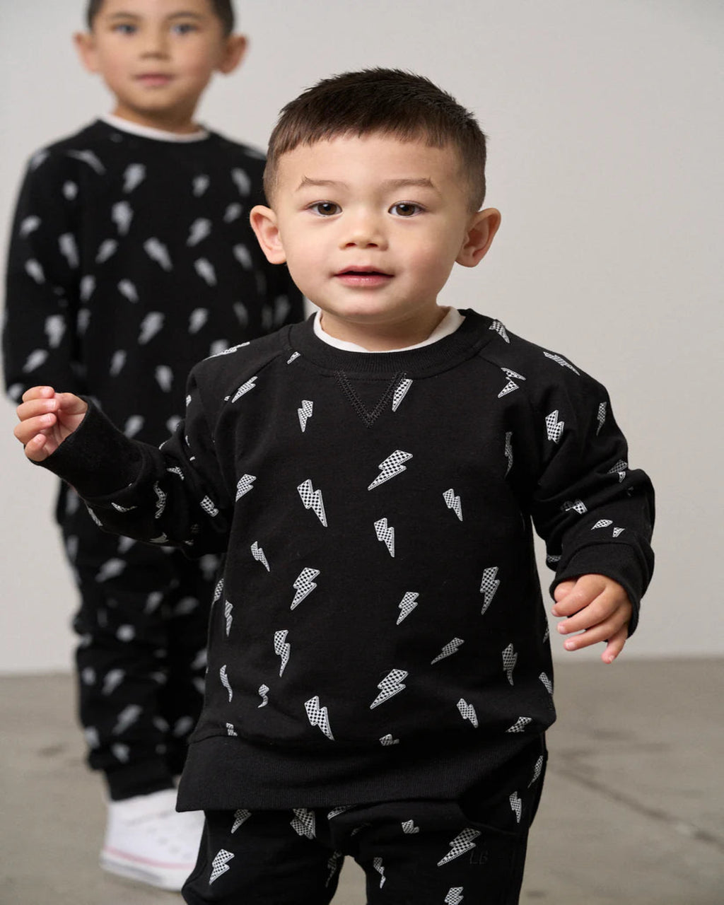 Two children wearing black pajamas with white patterns 