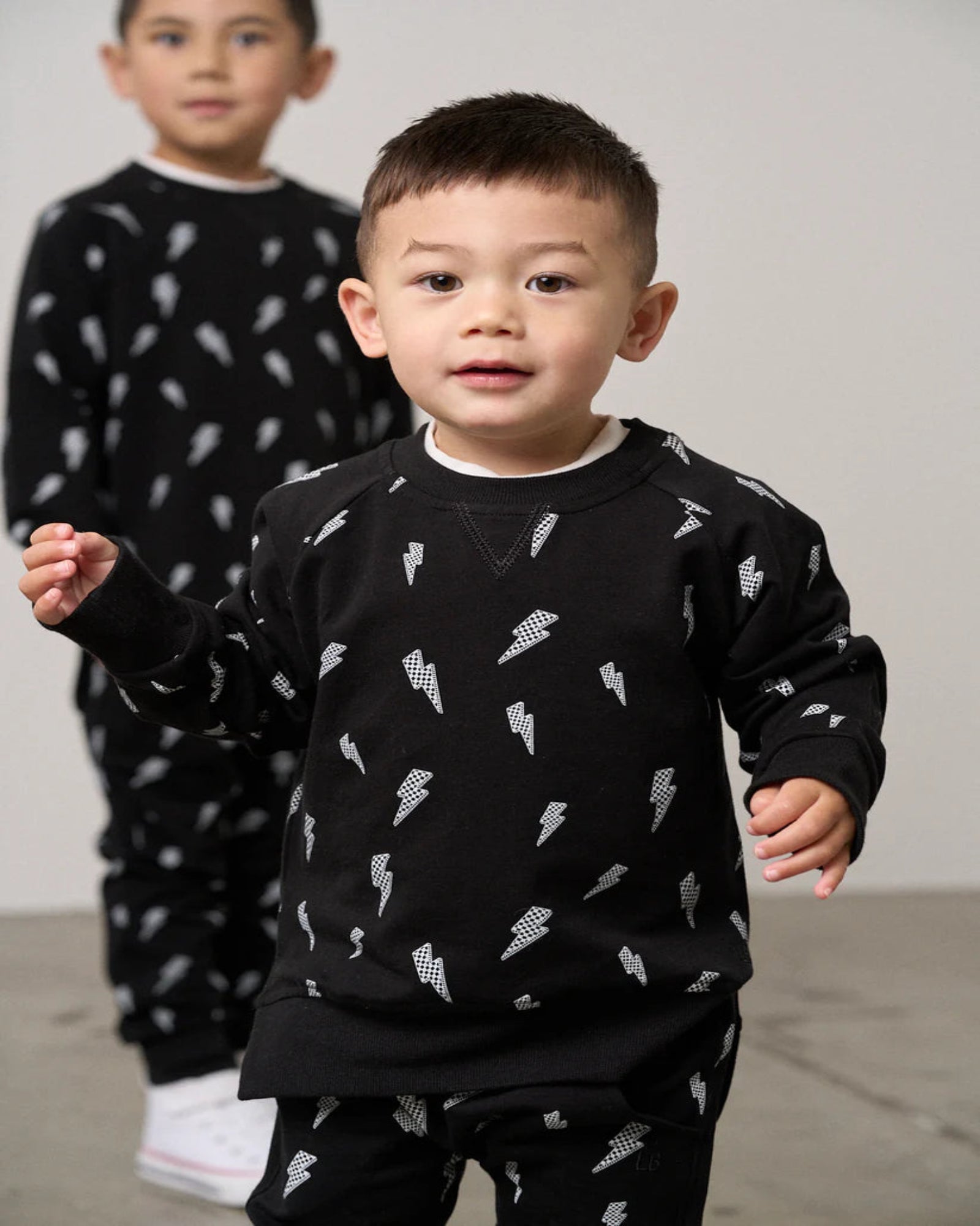 Two children wearing black pajamas with white patterns 