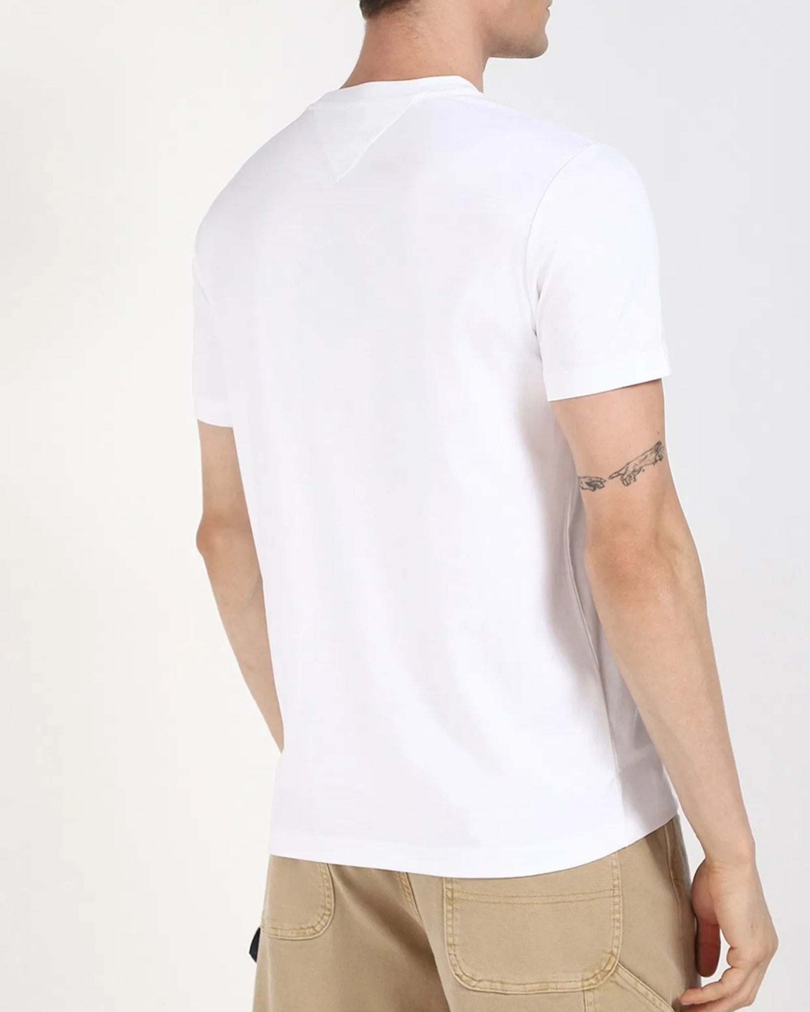 Person wearing a plain white t-shirt on a light gray background