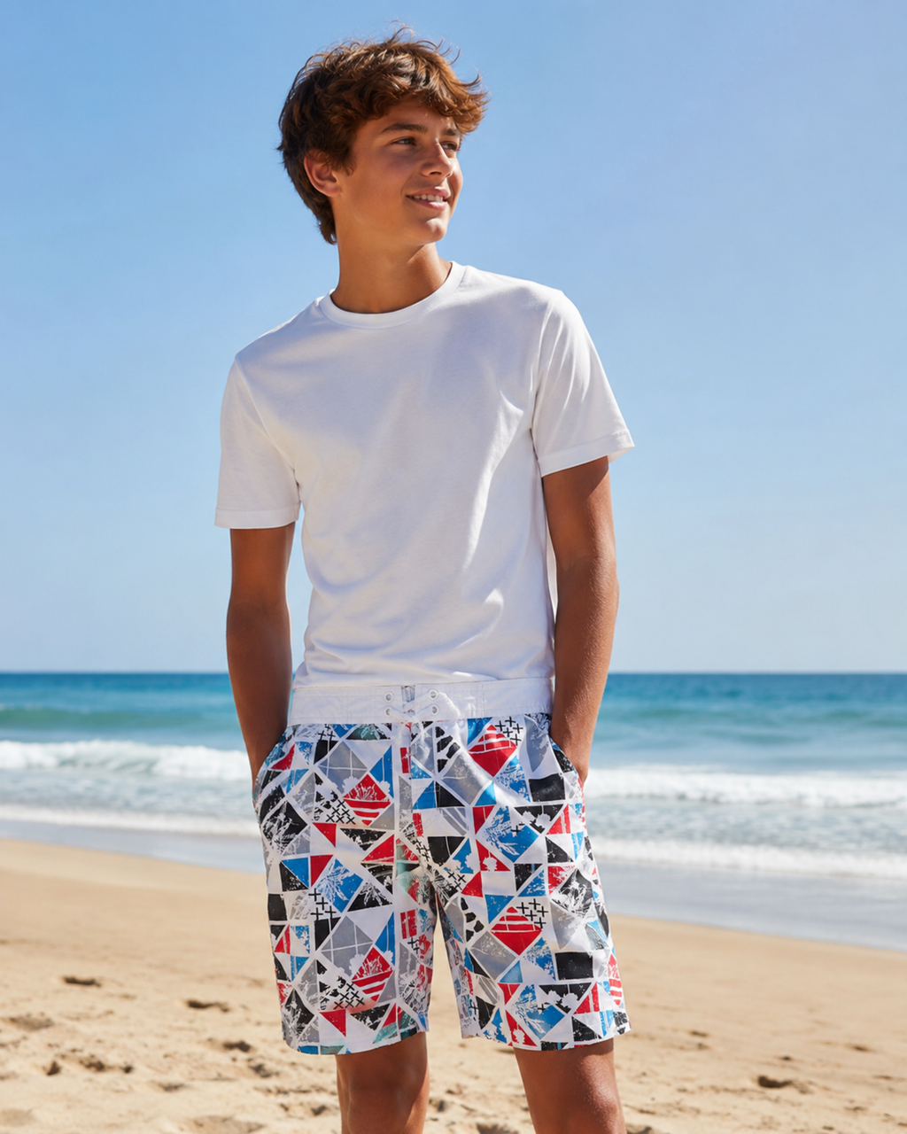 Person wearing a white t-shirt and colorful geometric shorts on a beach.
