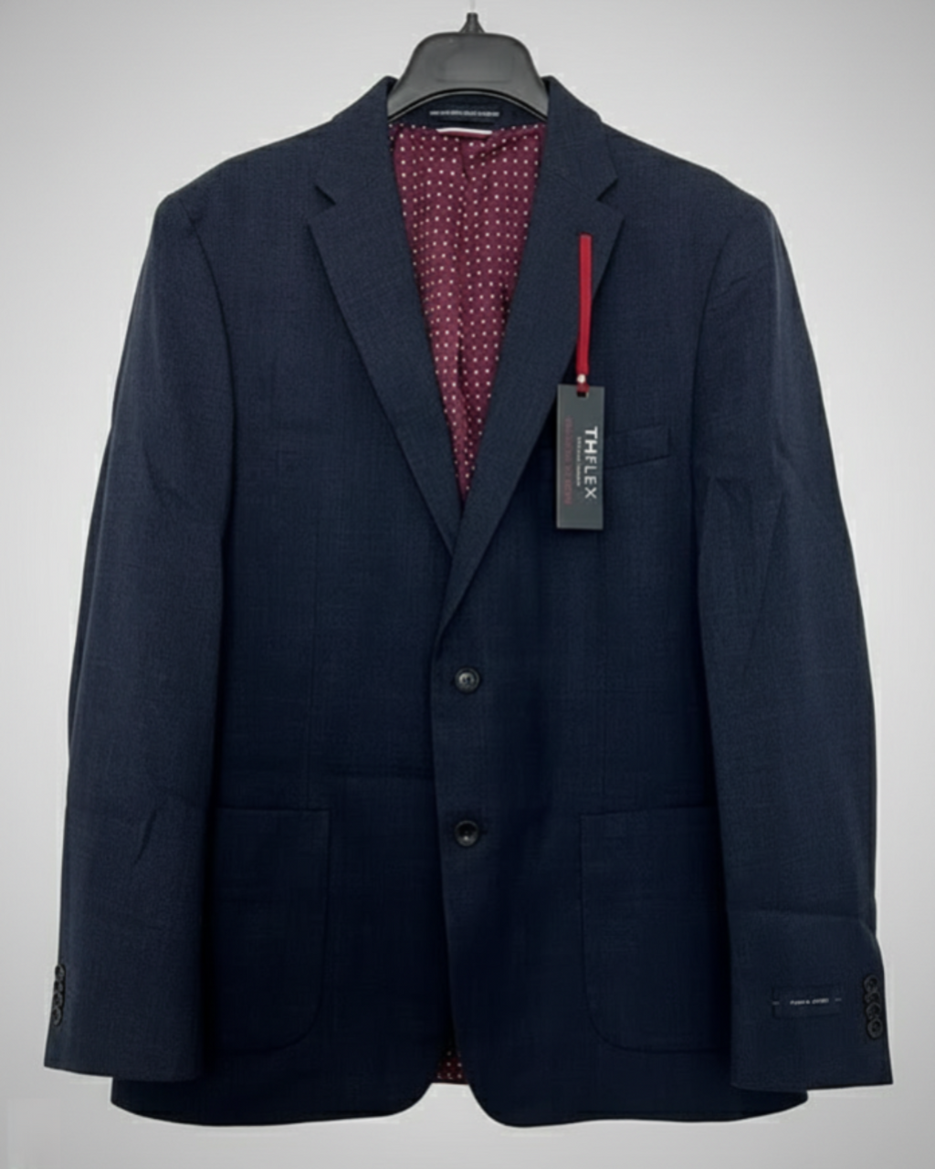 Navy blazer with a red patterned shirt underneath on a hanger against a white background