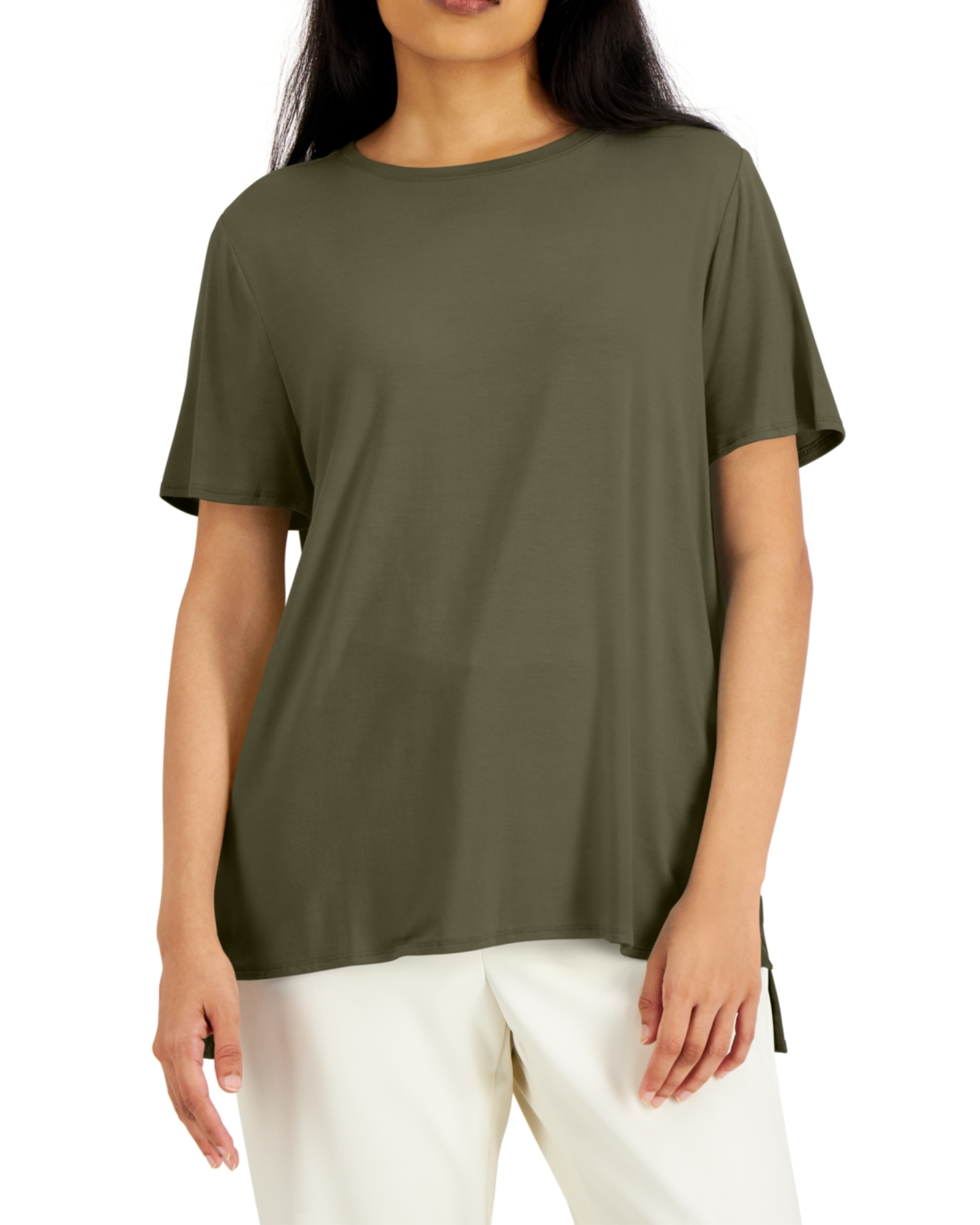 Woman wearing an olive green t-shirt and white pants on a white background
