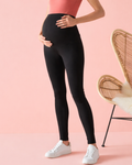 Pregnant women wearing black leggings and white sneakers on a pink background