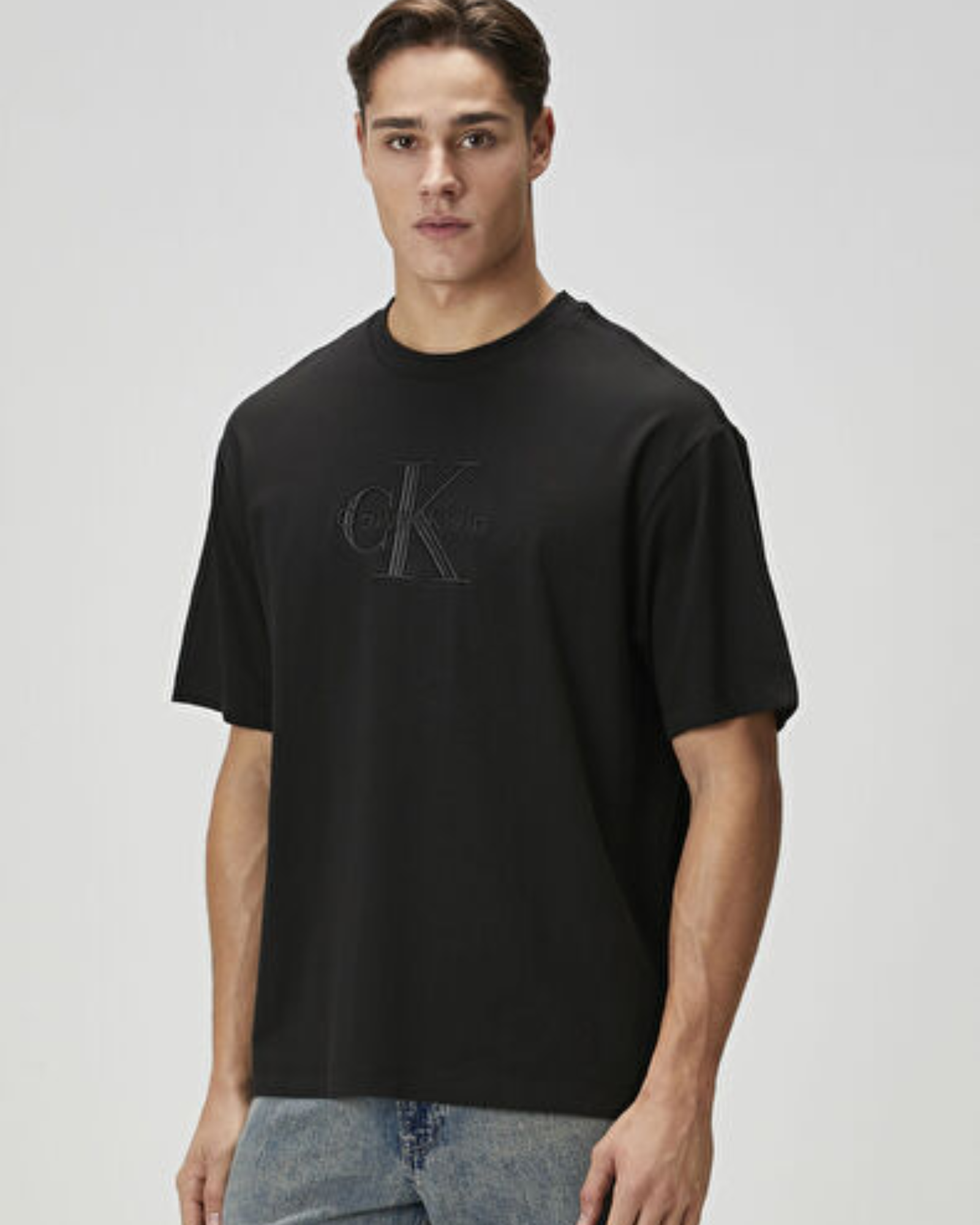 Man wearing a black t-shirt with a logo on a light gray background