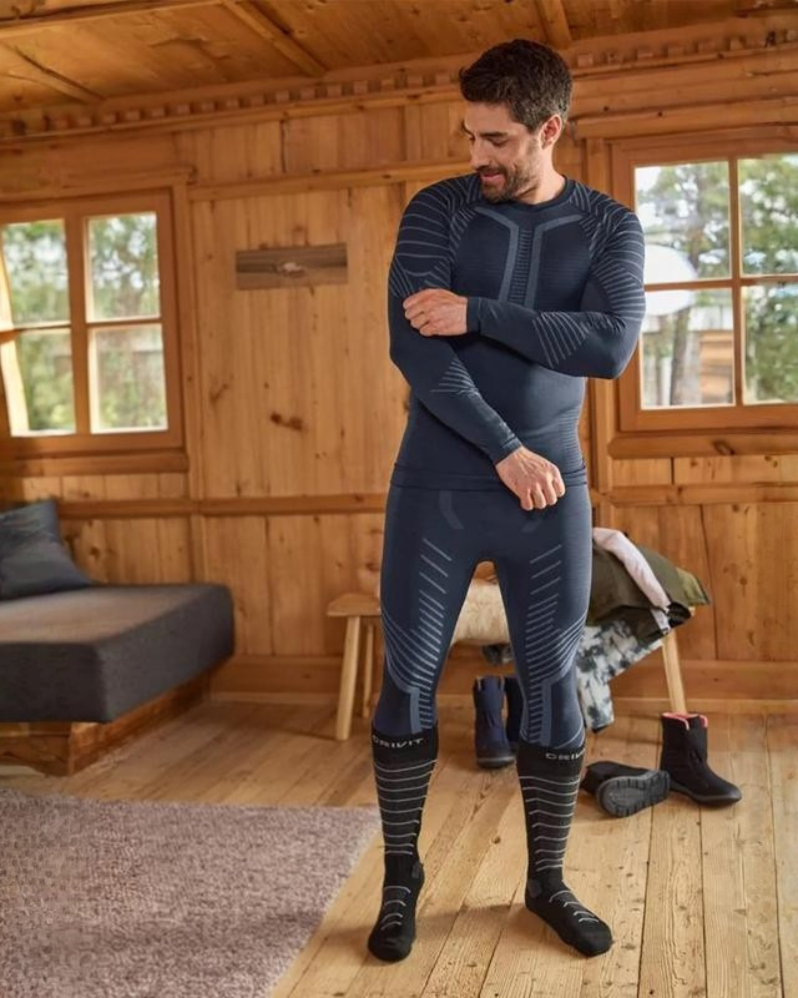 Man wearing a blue thermal outfit in a wooden cabin.