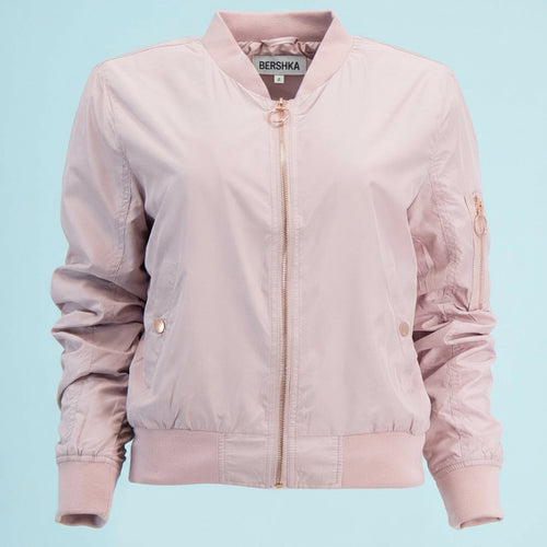Pink bomber jacket with gold zippers on a light blue background