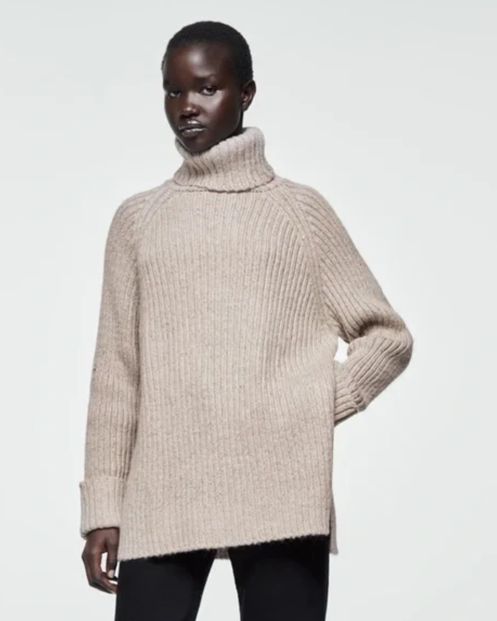 Person wearing a beige turtleneck sweater on a plain background