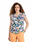 Woman wearing a colorful floral top and orange pants on a white background