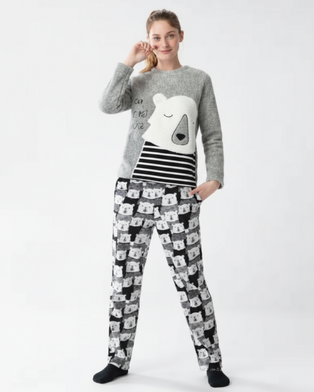 women wearing a gray pajama sweater with a white design and patterned pajama pants on a white background